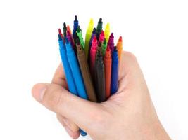 canetas marcadores multicoloridas com a mão no fundo branco. foto