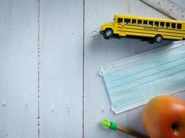 ônibus escolar e máscara na mesa de madeira para educação ou conceito médico foto