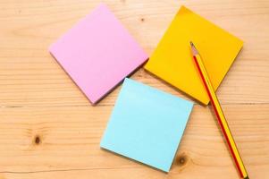 notas adesivas coloridas com lápis no fundo da mesa de madeira. foto