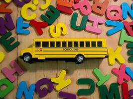 o alfabeto de madeira multi cores e ônibus escolar na mesa para educação ou conceito de criança foto