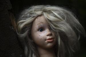 a cabeça da boneca está na lama. brinquedo infantil. cabeça de menina de borracha suja com cabelo. foto