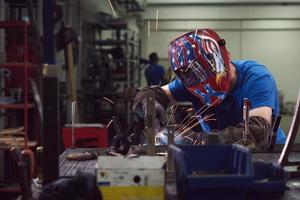 soldador profissional da indústria pesada trabalhando dentro da fábrica, usa capacete e começa a soldar. foco seletivo foto