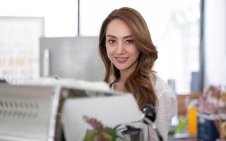 startup bem sucedido pequeno empresário sme beleza garota stand com smartphone tablet no restaurante café. retrato do proprietário do café barista mulher bronzeada asiática. conceito de negócio de vendedor de sme empreendedor foto