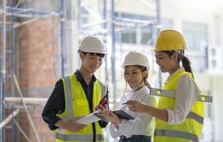 construção profissional e equipe de engenheiros trabalhando no local de trabalho. arquiteto negro profissional e trabalhador da construção civil trabalhando olham para o plano de planta no local. foto