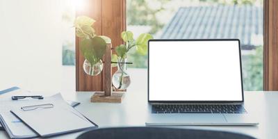 laptop de tela em branco e fundo de área de trabalho de pôster em um escritório moderno foto