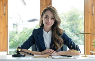 retrato, atraente e encantadora jovem empresária asiática ou gerente executiva feminina senta-se em sua mesa de escritório na moderna sala de escritório brilhante. foto