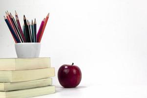 materiais de educação na caixa, maçã vermelha e livros isolados no fundo branco. de volta aos modelos de conceito de pôster da escola foto