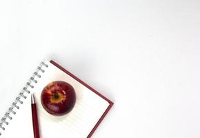 volta ao conceito de escola com materiais educativos, caderno, maçã, caneta isolada no fundo branco. vista superior dos elementos de estudo para modelos de conceitos de aprendizagem de crianças foto