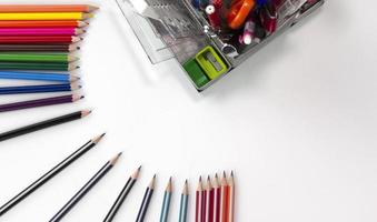 posição de lápis de cor criativa com elementos de educação no backgroup branco. usado no conceito de volta à escola. vista superior de lápis multicoloridos isolados no fundo branco foto