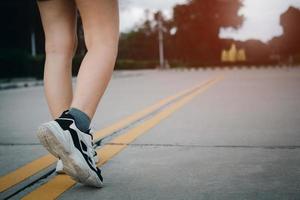 close-up de sapatos de mulher jovem caminhando ao ar livre em tênis de corrida por trás. foto