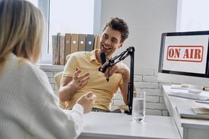 jovem feliz gravando entrevista de podcast com convidado em estúdio foto