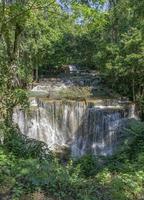 muitas cachoeiras fluem no quadro de plantas e árvores verdes. mirante da cachoeira huai mae kamin, província de kanchanaburi foto