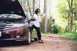 mulher asiática chamando reparador ou equipe de seguros para corrigir um problema de motor de carro em uma estrada local - pessoas com conceito de transporte de problema de carro foto