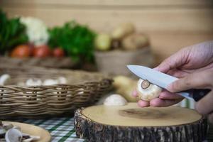 senhora cozinha cogumelo champignon fresco vegetal na cozinha - pessoas com conceito de culinária vegetal foto