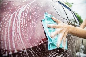 homem lavar carro usando shampoo - conceito de cuidado de carro de vida diária foto