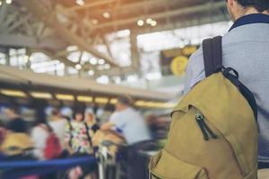 imagem focada suave do viajante sobre a longa fila de passageiros borrada esperando o check-in nos balcões de check-in do aeroporto foto