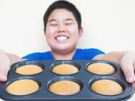 desfocagem do garoto mostrando, servindo seus muffins caseiros. foto é foco em muffins.