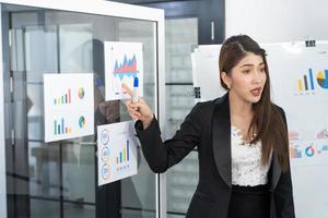 linda empresária dá relatório, apresentação para seus colegas de trabalho na sala de conferências, ela mostra gráficos. profissional de negócios feminino de sucesso. foto