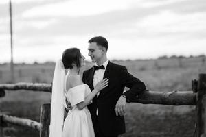 jovem casal o noivo em um terno preto e a noiva em um vestido curto branco foto