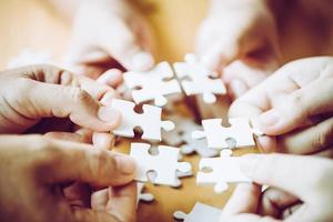 mãos de uma pessoa criança e pai jogando jogo de peças de quebra-cabeça juntos na mesa de madeira em casa, conceito de lazer com a família, brincar com o desenvolvimento infantil, educação e diversão. foto