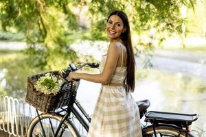 jovem mulher com flores na cesta de bicicleta elétrica foto