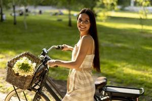 jovem mulher com flores na cesta de bicicleta elétrica foto