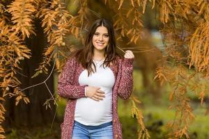 jovem mulher grávida no parque outono foto