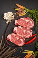 três pedaços de carne bovina fresca com legumes foto