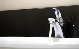 torneira aberta e fluxo de água em um banheiro foto