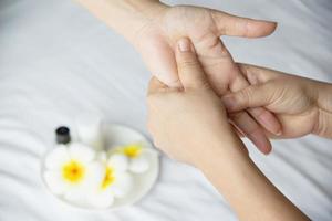 massagem de spa de mão sobre fundo de cama branca limpa - as pessoas relaxam com serviço de massagem de mão foto