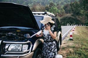 mulher asiática chamando reparador ou equipe de seguros para corrigir um problema de motor de carro em uma estrada local - pessoas com conceito de transporte de problema de carro foto