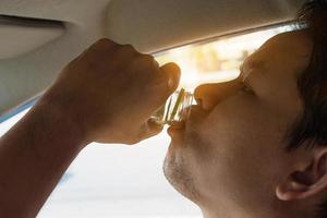 homem tomando bebida saudável enquanto dirige cuidado para refresco acordado e unidade robusta - dirija com segurança com algum conceito de bebida refrescante foto