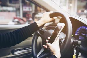 close-up de uma mulher dirigindo um carro perigosamente ao usar o telefone celular foto