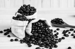 saco de grãos de café sobre fundo de madeira em tom preto e branco foto