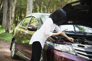 mulher asiática chamando reparador ou equipe de seguros para corrigir um problema de motor de carro em uma estrada local - pessoas com conceito de transporte de problema de carro foto