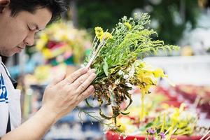 homem asiático segurando flores amarelas frescas para participação na cerimônia budista tradicional local - pessoas com conceito de relacionamento religioso foto