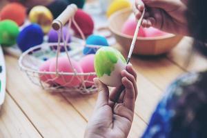 pessoas pintando ovos de páscoa coloridos - conceito de celebração do feriado de páscoa foto