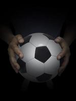 bola de futebol na mão masculina em fundo preto foto