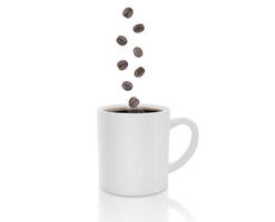xícara de café com fumaça caindo grãos de café no fundo branco foto