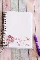 página de caderno em branco com flores e caneta na mesa de madeira foto