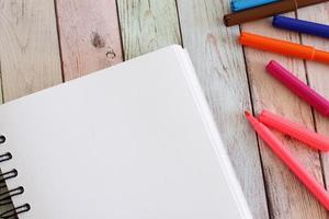 página em branco do caderno e canetas coloridas foto