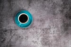 café preto em uma xícara de cerâmica azul no antigo chão de cimento cinza foto