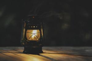 lâmpada de querosene antiga com luzes no chão de madeira à noite foto