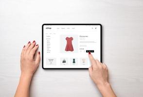 compras on-line com um tablet. vestido vermelho feminino na página de comércio eletrônico
