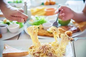 as pessoas gostam de comer espaguete juntos em um grande conjunto de refeições - tempo feliz em família com o conceito de comida foto