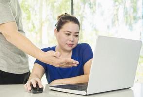 um homem está treinando uma mulher que trabalha com computador no escritório moderno foto
