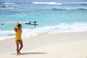 bali, indonésia 22 de novembro de 2021 salva-vidas observando a situação no mar enquanto traz uma prancha de surf foto