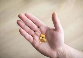 vitaminas e suplementos. o homem está segurando pílulas na mão direita. pílulas na mão representando o conceito de saúde, ajuda e medicina foto