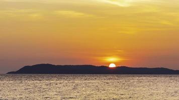 paisagem do pôr do sol colorido brilhando sobre as águas laranja brilhantes do oceano. ilha paradisíaca silhueta do belo pôr do sol tropical na praia de koh larn em pattaya. foco suave em fundos de pôr do sol foto