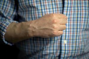 um homem aperta os botões de uma camisa xadrez com a mão direita foto